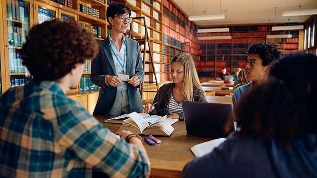 Gruppe Schüler und eine Lehrerin in einer Bibliothek