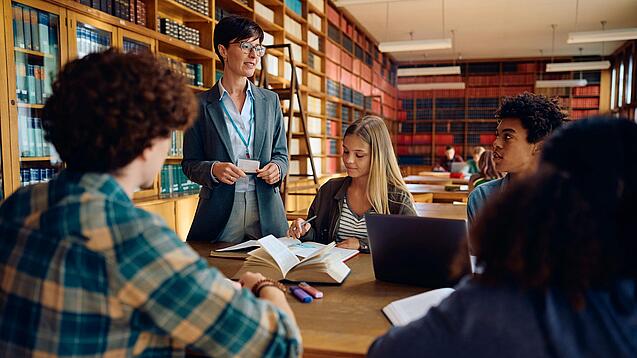 Gruppe Schüler und eine Lehrerin in einer Bibliothek