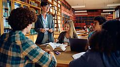 Gruppe Schüler und eine Lehrerin in einer Bibliothek