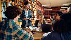 Gruppe Schüler und eine Lehrerin in einer Bibliothek