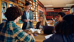Gruppe Schüler und eine Lehrerin in einer Bibliothek