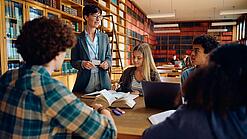 Gruppe Schüler und eine Lehrerin in einer Bibliothek
