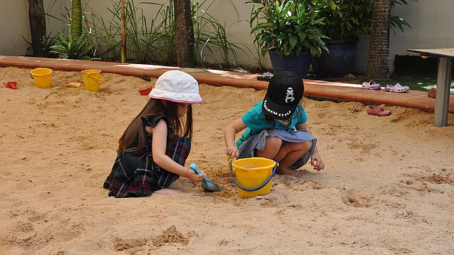 Zwei Kinder spielen im Sandkasten.