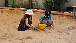 Zwei Kinder spielen im Sandkasten.
