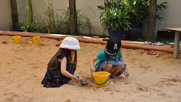Zwei Kinder spielen im Sandkasten.