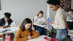 Eine Lehrerin schaut einer Schülerin beim Lernen zu.