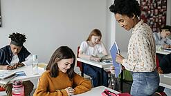 Eine Lehrerin schaut einer Schülerin beim Lernen zu.