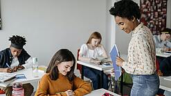 Eine Lehrerin schaut einer Schülerin beim Lernen zu.