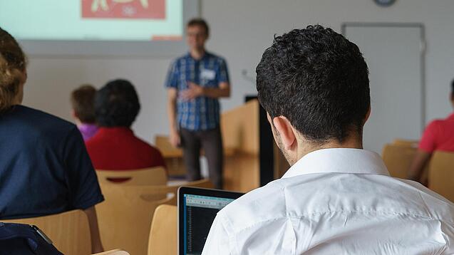 Ein Student hört sich einen Vortrag eines Dozenten an.