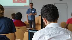 Ein Student hört sich einen Vortrag eines Dozenten an.