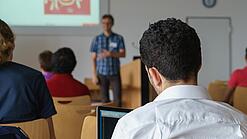 Ein Student hört sich einen Vortrag eines Dozenten an.