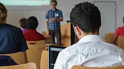 Ein Student hört sich einen Vortrag eines Dozenten an.