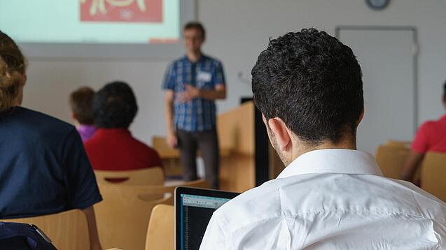 Ein Student hört sich einen Vortrag eines Dozenten an.