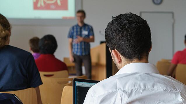 Ein Student hört sich einen Vortrag eines Dozenten an.