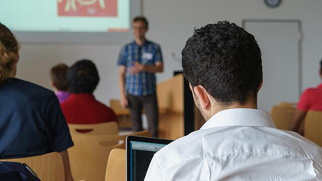 Ein Student hört sich einen Vortrag eines Dozenten an.