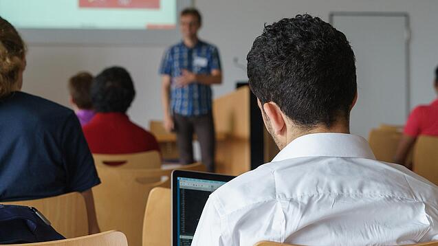 Ein Student hört sich einen Vortrag eines Dozenten an.