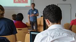 Ein Student hört sich einen Vortrag eines Dozenten an.