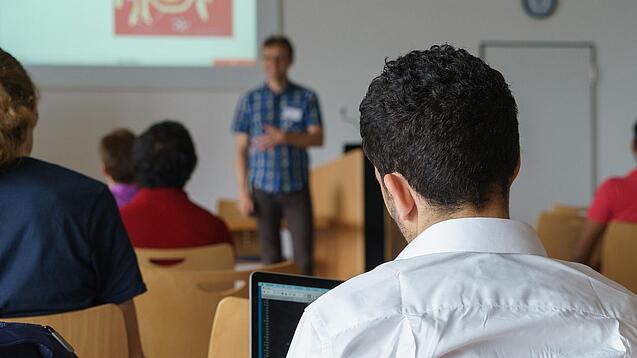 Ein Student hört sich einen Vortrag eines Dozenten an.