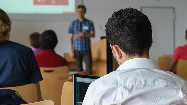 Ein Student hört sich einen Vortrag eines Dozenten an.