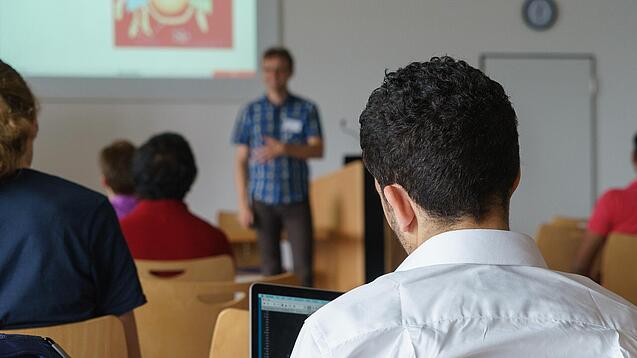 Ein Student hört sich einen Vortrag eines Dozenten an.
