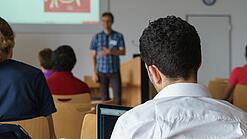 Ein Student hört sich einen Vortrag eines Dozenten an.