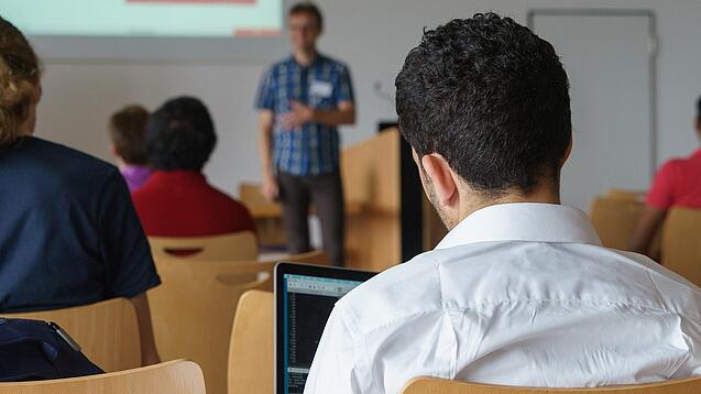 Ein Student hört sich einen Vortrag eines Dozenten an.
