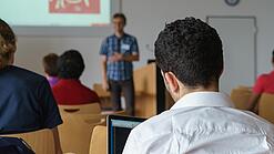 Ein Student hört sich einen Vortrag eines Dozenten an.