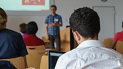 Ein Student hört sich einen Vortrag eines Dozenten an.