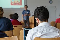 Ein Student hört sich einen Vortrag eines Dozenten an.