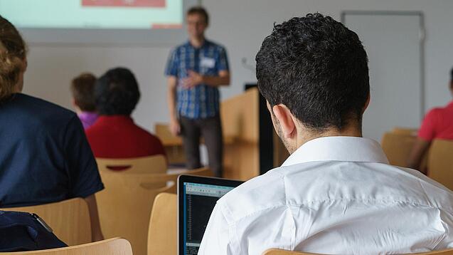 Ein Student hört sich einen Vortrag eines Dozenten an.