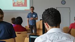 Ein Student hört sich einen Vortrag eines Dozenten an.