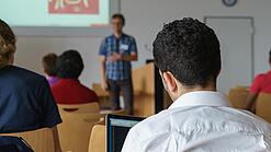 Ein Student hört sich einen Vortrag eines Dozenten an.