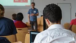 Ein Student hört sich einen Vortrag eines Dozenten an.