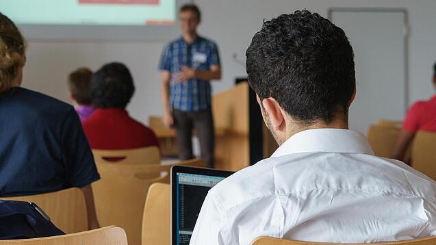 Ein Student hört sich einen Vortrag eines Dozenten an.