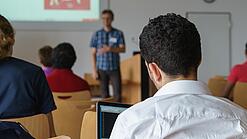 Ein Student hört sich einen Vortrag eines Dozenten an.