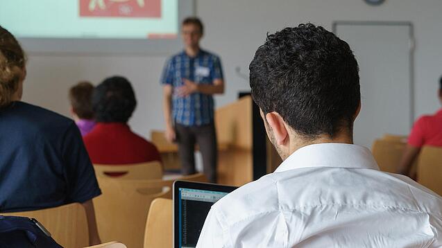 Ein Student hört sich einen Vortrag eines Dozenten an.