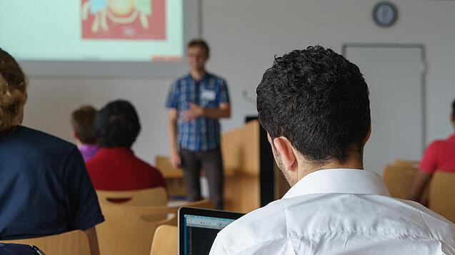 Ein Student hört sich einen Vortrag eines Dozenten an.