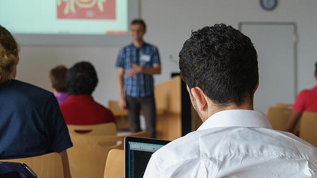 Ein Student hört sich einen Vortrag eines Dozenten an.