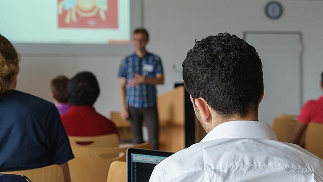 Ein Student hört sich einen Vortrag eines Dozenten an.