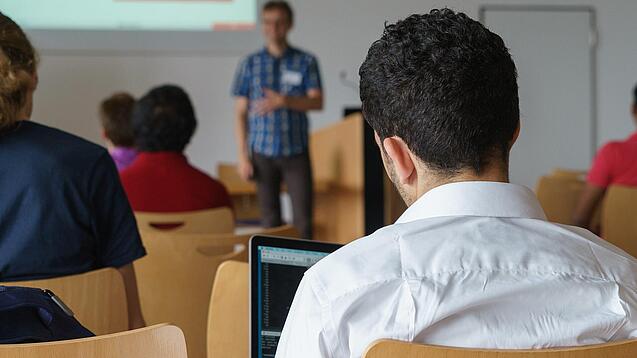 Ein Student hört sich einen Vortrag eines Dozenten an.
