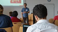 Ein Student hört sich einen Vortrag eines Dozenten an.