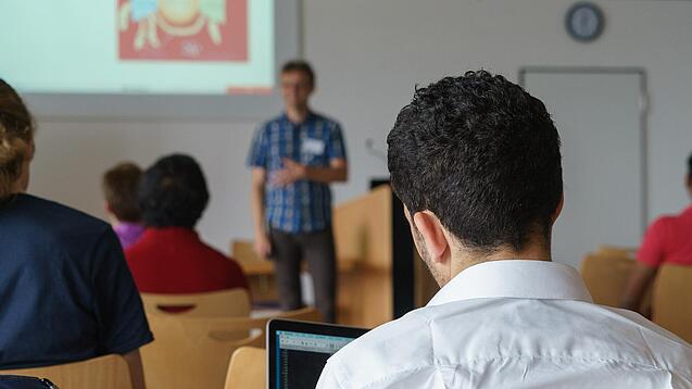Ein Student hört sich einen Vortrag eines Dozenten an.