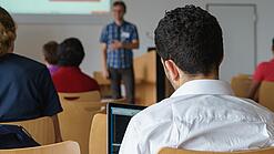 Ein Student hört sich einen Vortrag eines Dozenten an.