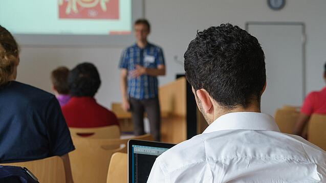 Ein Student hört sich einen Vortrag eines Dozenten an.