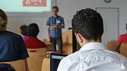 Ein Student hört sich einen Vortrag eines Dozenten an.