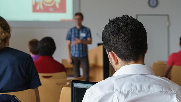 Ein Student hört sich einen Vortrag eines Dozenten an.
