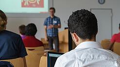 Ein Student hört sich einen Vortrag eines Dozenten an.