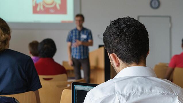 Ein Student hört sich einen Vortrag eines Dozenten an.