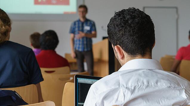 Ein Student hört sich einen Vortrag eines Dozenten an.