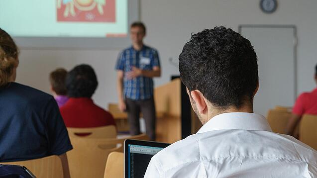 Ein Student hört sich einen Vortrag eines Dozenten an.